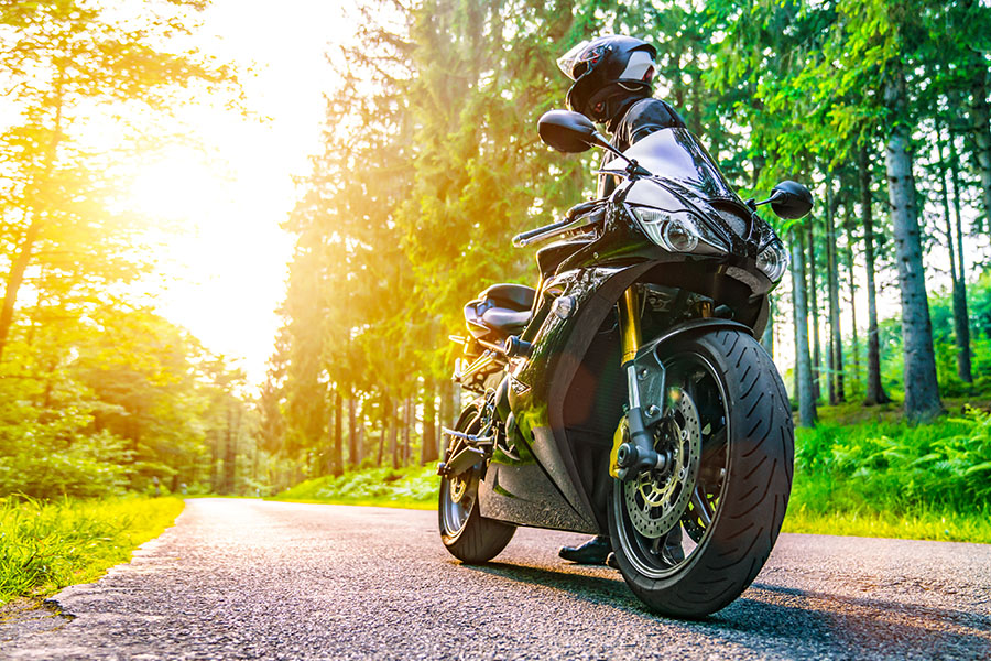 Blog - Motorcycle Parked on Road in a Forest Area on a Sunny Day